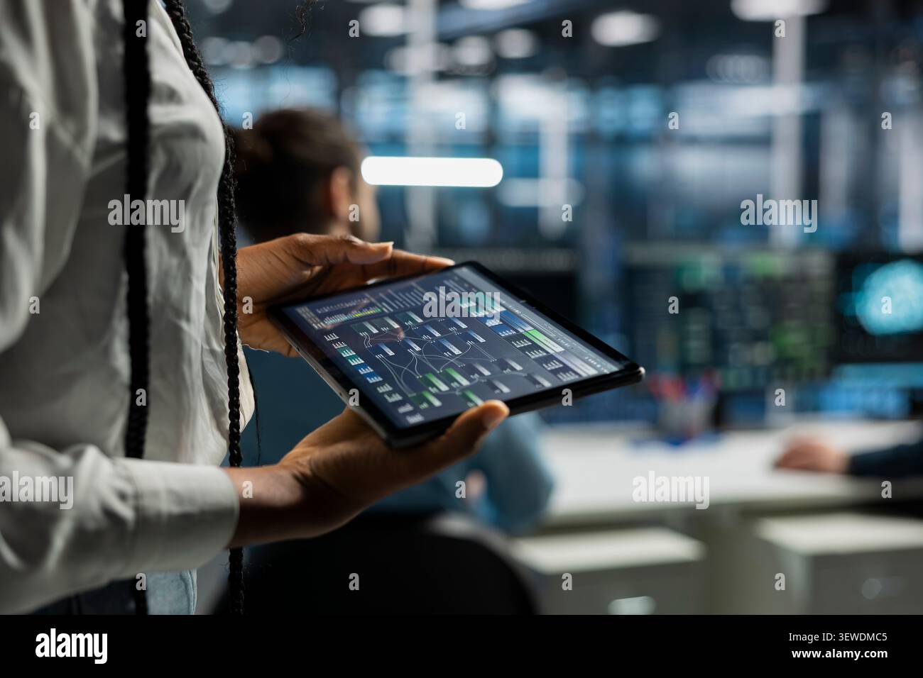 Data center programmer uses a digital tablet in a data center to manage AI systems and optimize server infrastructure. Stock Photo