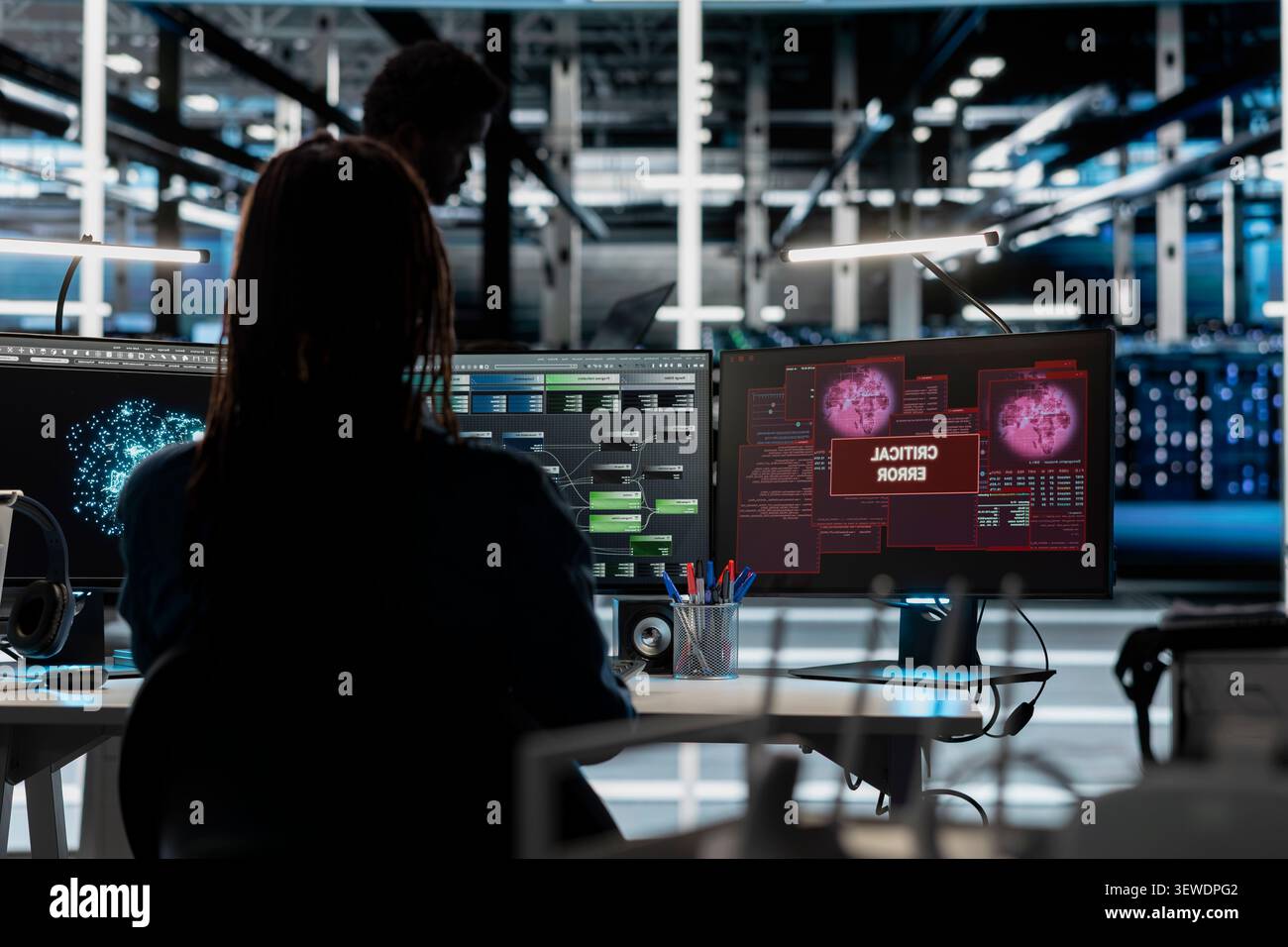 Concerned IT employee reviews warning messages in a data center while troubleshooting errors affecting equipment performance. Stock Photo
