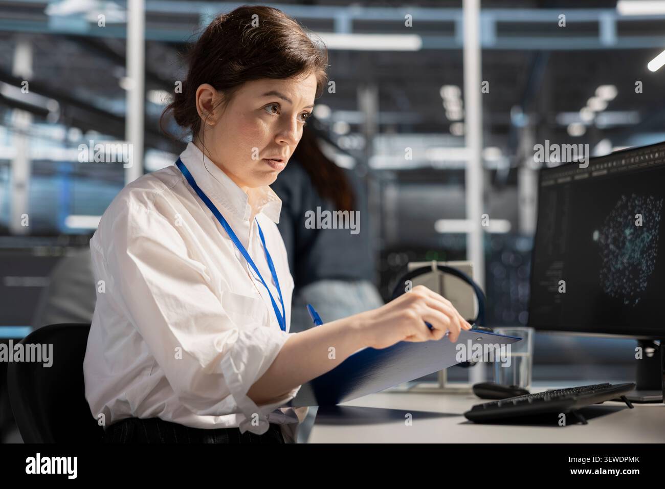 System operator reviews performance analytics on a desktop computer in a data center to optimize storage systems and resource use. Stock Photo