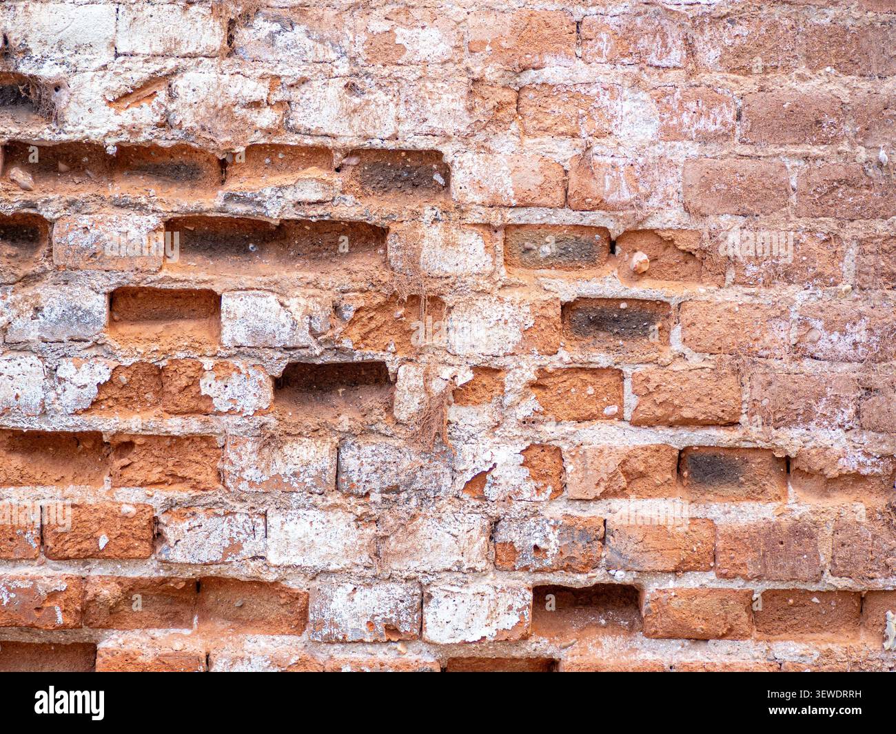 Damaged brick wall texture with crumbling white mortar creating an aged pattern Stock Photo