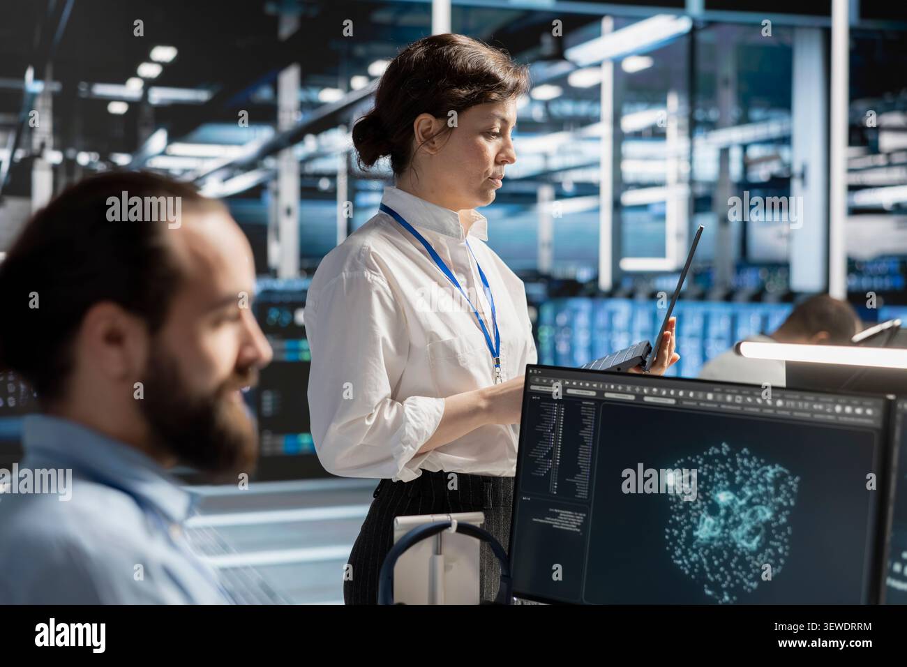 Data center team uses a desktop computer in a data center to manage AI virtualization and optimize server infrastructure. Stock Photo