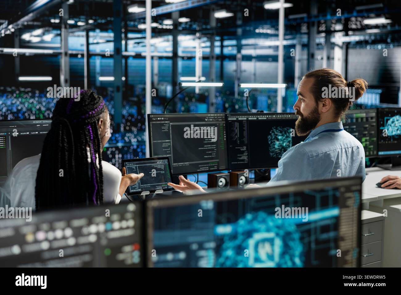 Man works with a computer workstation in a server room to support artificial intelligence systems. Stock Photo