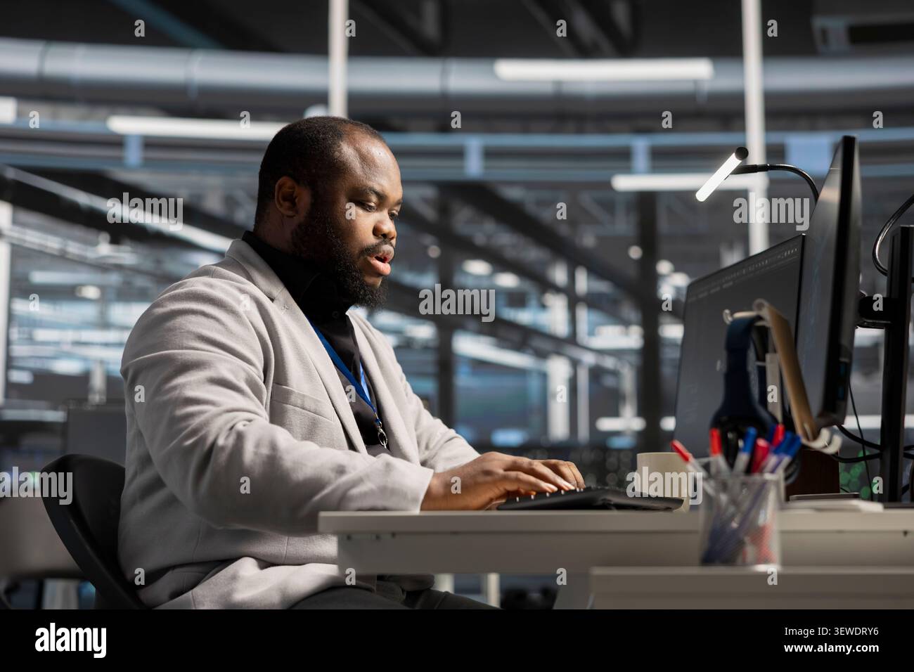 System administrator uses a computer to run diagnostics, update servers and check infrastructure performance. Stock Photo