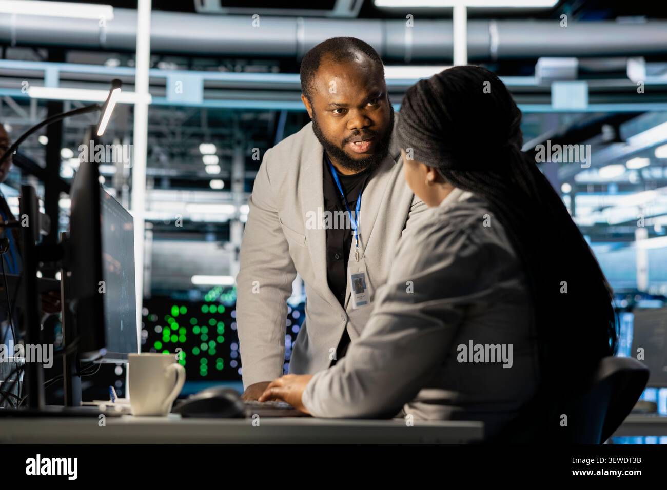 Data center colleagues collaborate on coding and AI automation scripts while reviewing server infrastructure together. Stock Photo