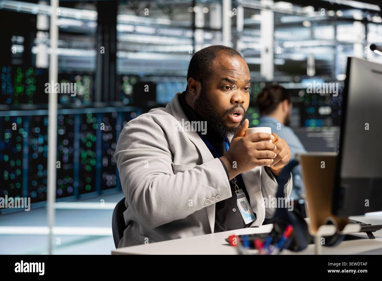 Data center technician uses a computer to run diagnostics, update servers and check infrastructure performance. Stock Photo