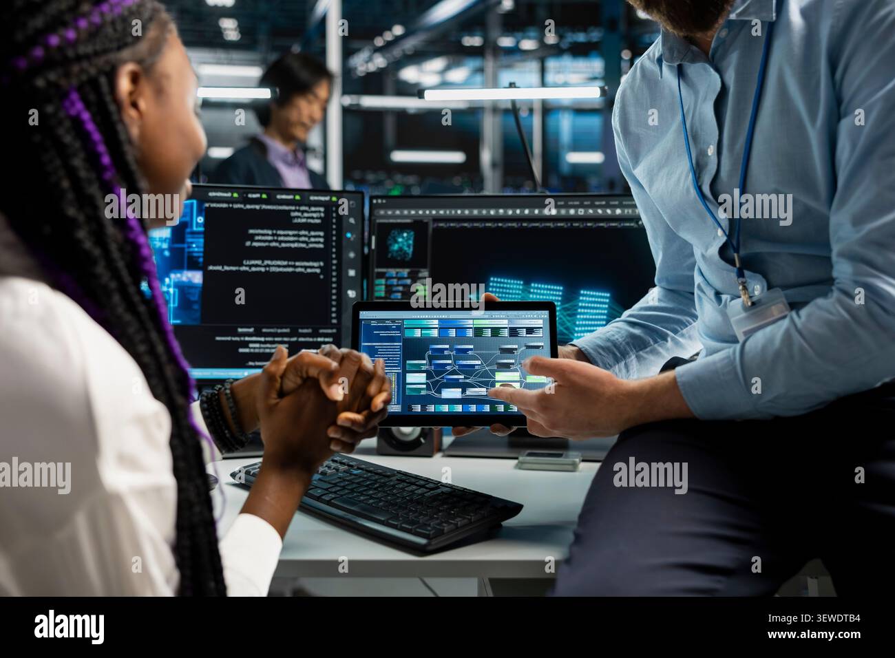 Data center programmer reviews AI systems and neural network parameters on a tablet inside a data center. Stock Photo