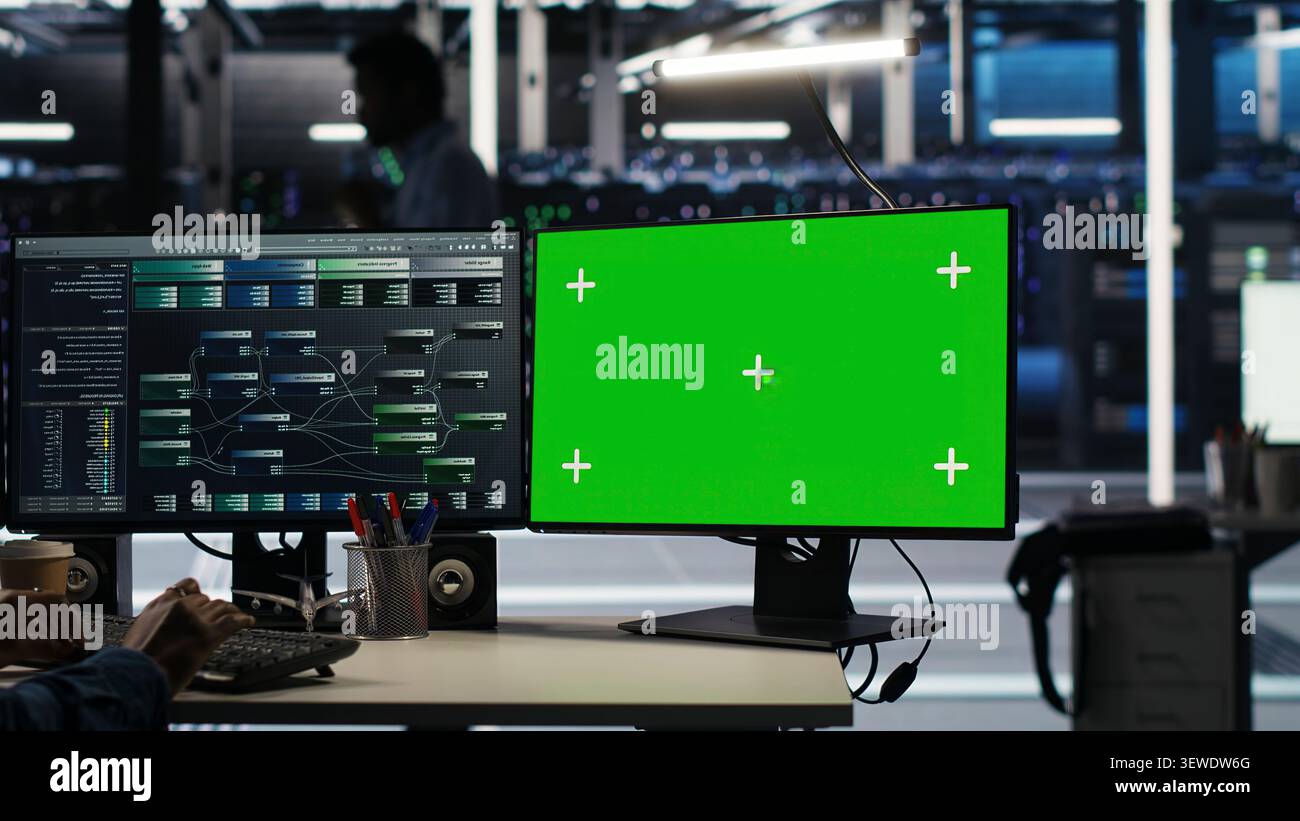 Engineer uses a green screen computer in a server farm to categorize unstructured data with node tree systems. Stock Photo