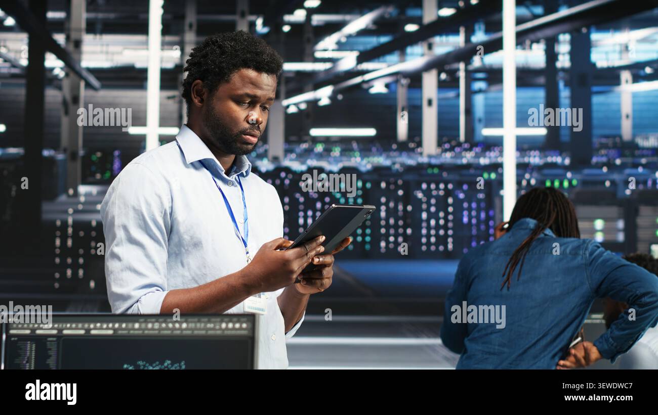 Data center technician uses a tablet with node tree programming to optimize resource allocation and analytics. Stock Photo