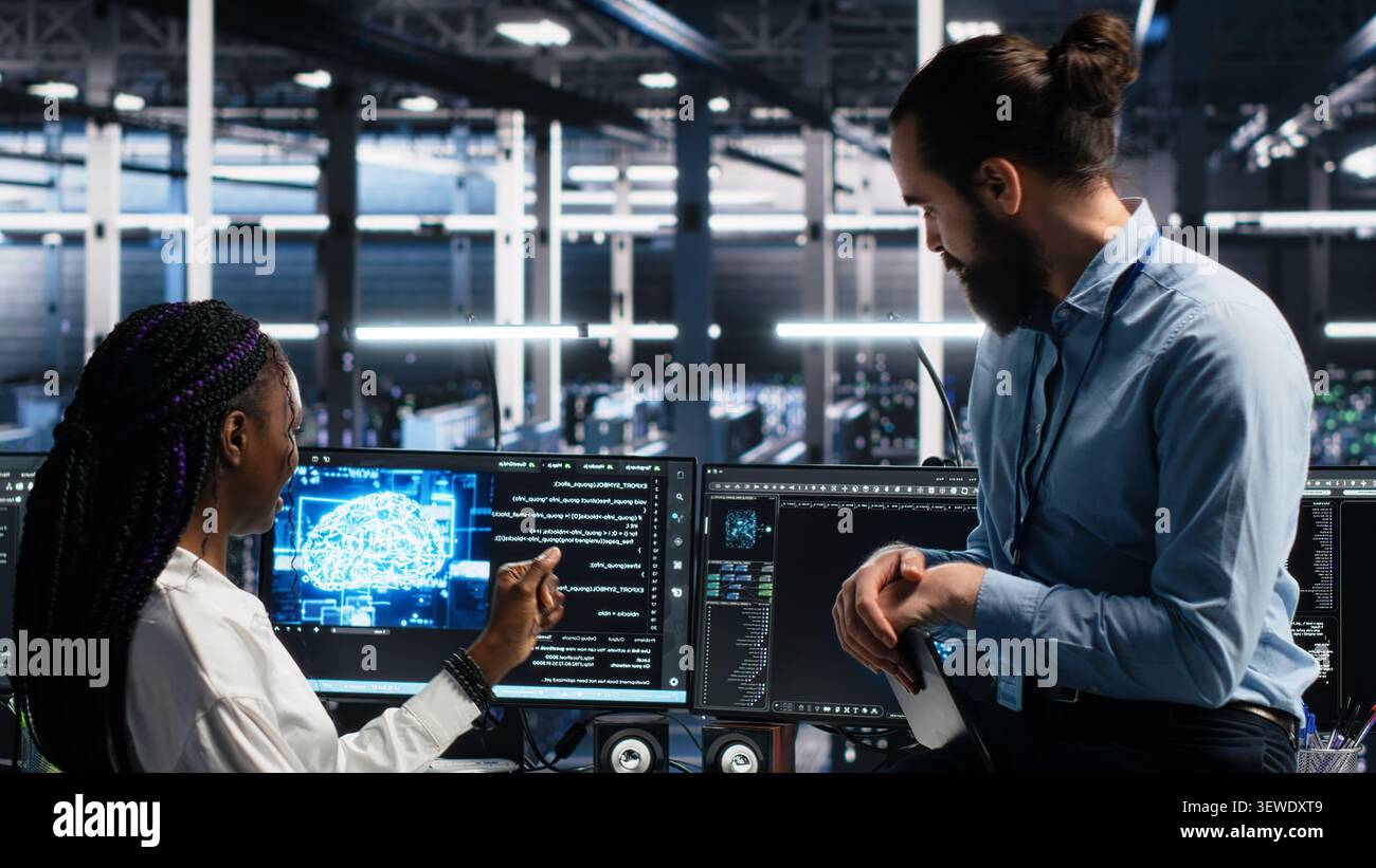 Data center engineering team uses deep learning tools on a digital device in a server room to improve AI operations and system efficiency. Stock Photo