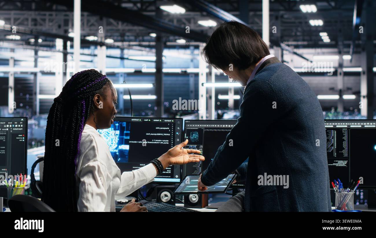 Asian man programs on a computer workstation in a data center with generative AI assistance. Stock Photo