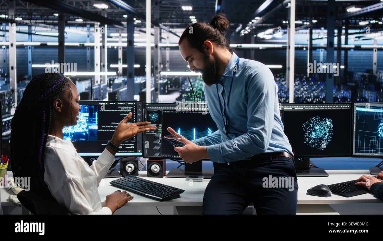 Woman programs on a computer workstation in a data center with generative AI assistance. Stock Photo