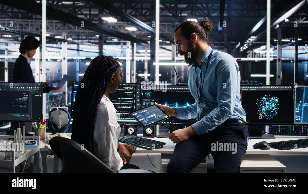 System administrator and employee programs on a computer workstation in a server hub with generative AI assistance. Stock Photo