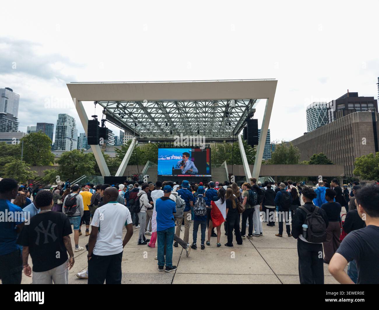Toronto City Hall displays a bright FIFA World Cup 2026 banner across its curved façade, with visitors gathered below near an information tent, captur - Smartphone Captured Stock Image