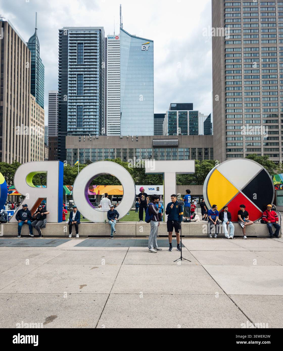 Toronto City Hall displays a bright FIFA World Cup 2026 banner across its curved façade, with visitors gathered below near an information tent, captur - Smartphone Captured Stock Image