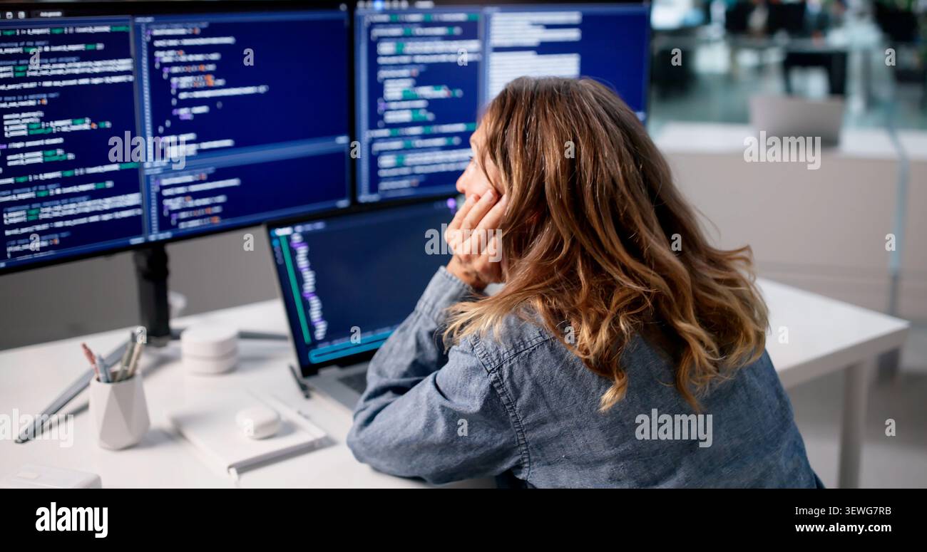 Frustrated Woman Developer Looks Tired While Fixing Coding Mistakes At Office. Stock Photo
