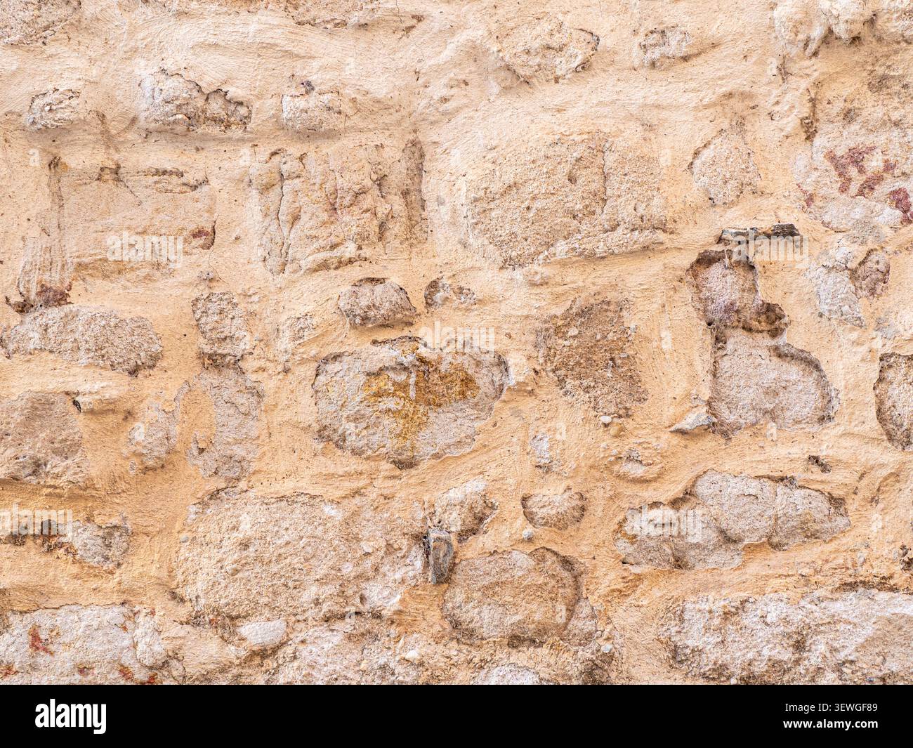 Rustic stone wall featuring textured surface with visible erosion and rough construction Stock Photo