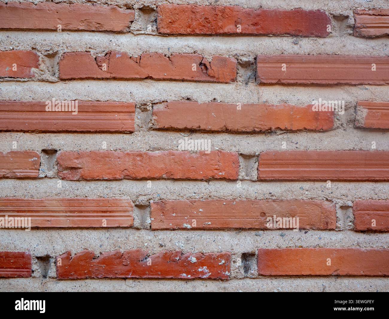 Red brick wall displaying textured surface with rough mortar joints Stock Photo