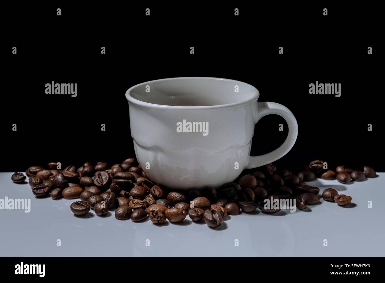 A white porcelain coffee cup surrounded by coffee beans Stock Photo