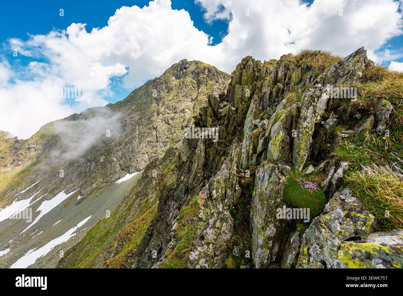 mountain landscape with steep rocky slopes. romania travel background. clouds on a blue sky above fagaras mountain ridge. stunning weather in summer Stock Photo