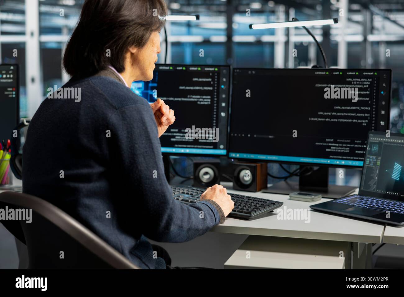 Computer scientist uses a desktop computer in a data center to support supercomputer management and reliable server workflows. Stock Photo
