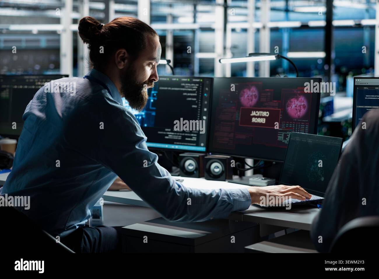 Technician works with a computer workstation in a server hub to support artificial intelligence systems. Stock Photo
