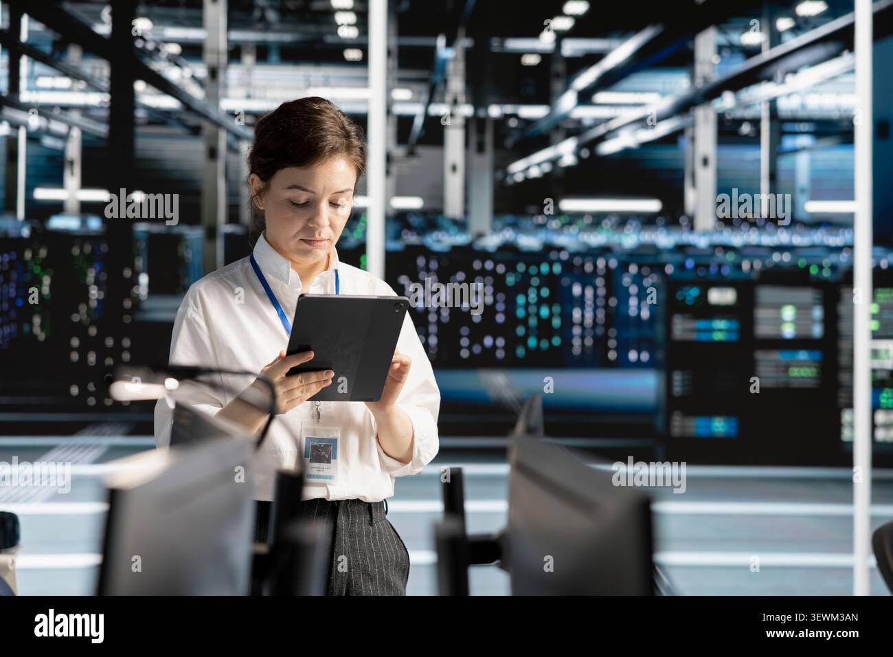 Data center engineer reviews AI systems and neural network parameters on a tablet inside a data center. Stock Photo