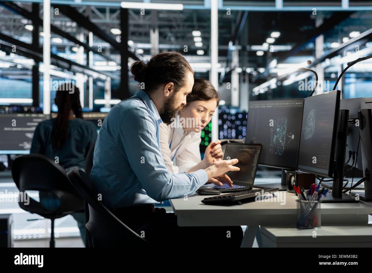 Data center colleagues collaborate on coding and AI automation scripts while reviewing server infrastructure together. Stock Photo