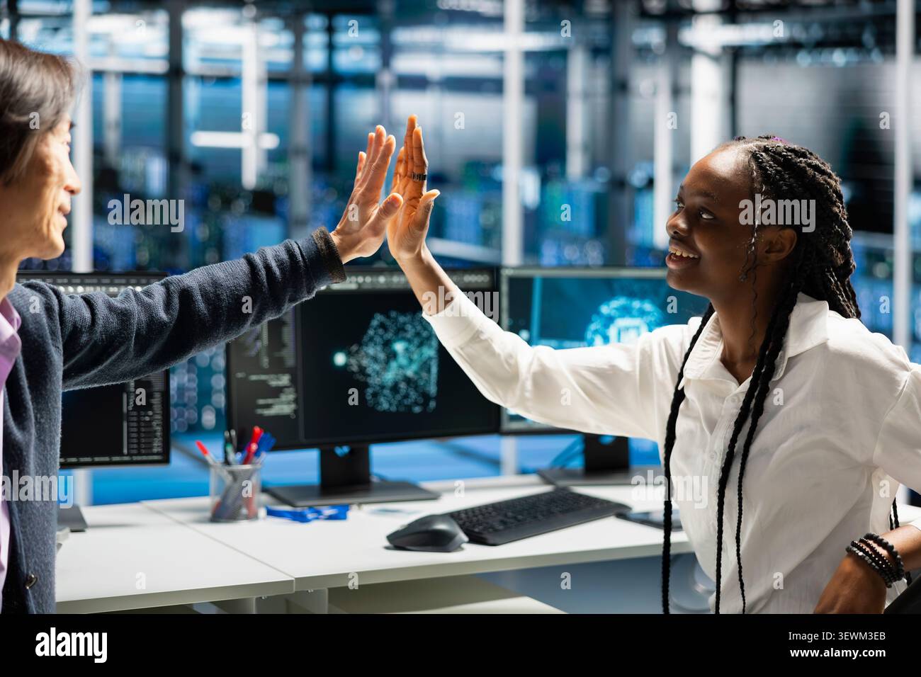 Delighted data center colleagues share a high five after improving system efficiency and completing AI implementation. Stock Photo
