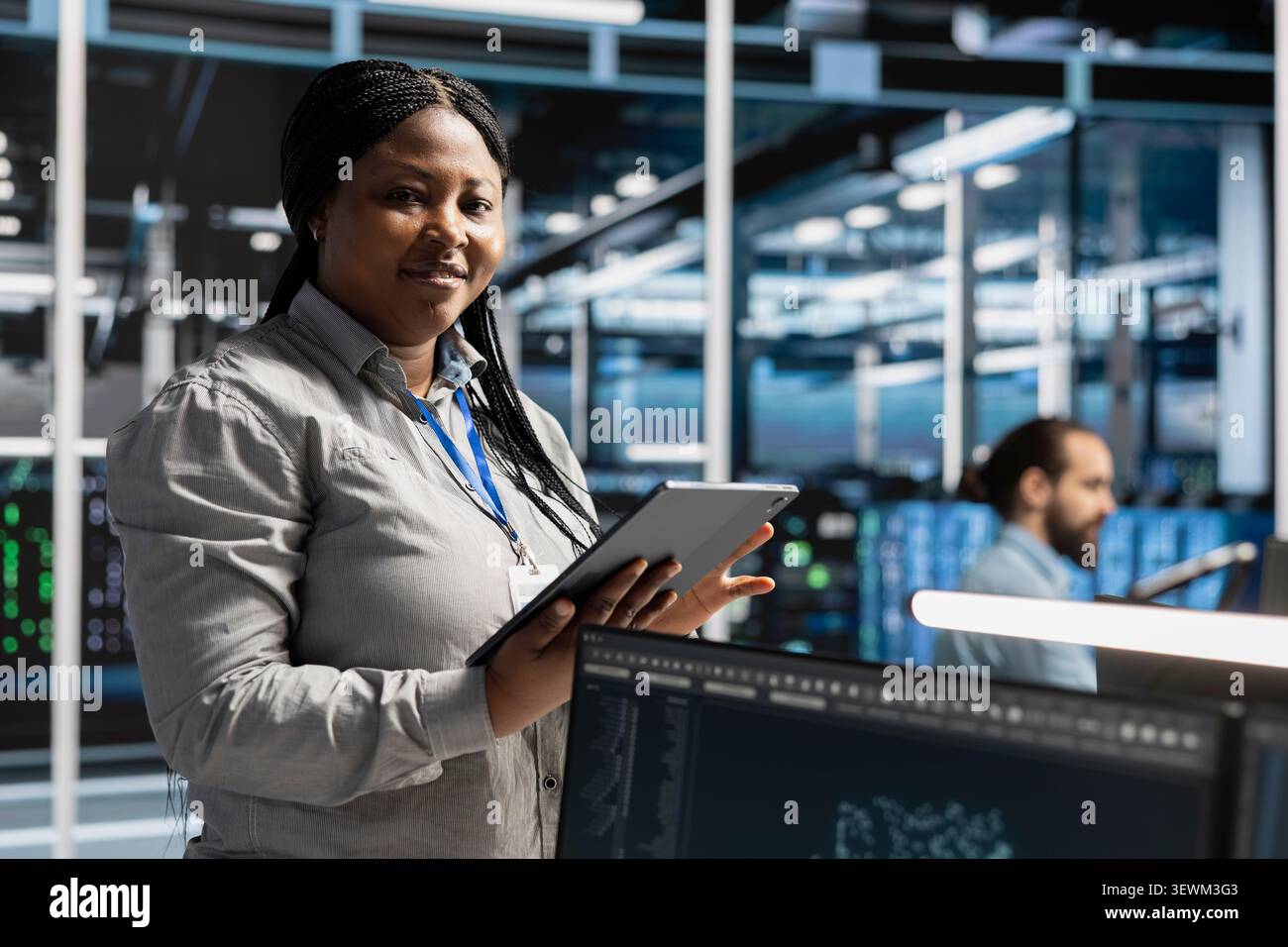 Smiling data center programmer uses a tablet to review server infrastructure, diagnostics and AI technology in a data center. Stock Photo