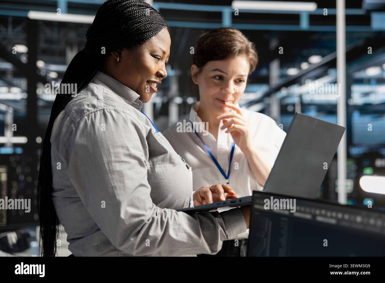Smiling data center team works with digital devices while reviewing systems, scripts and server infrastructure. Stock Photo