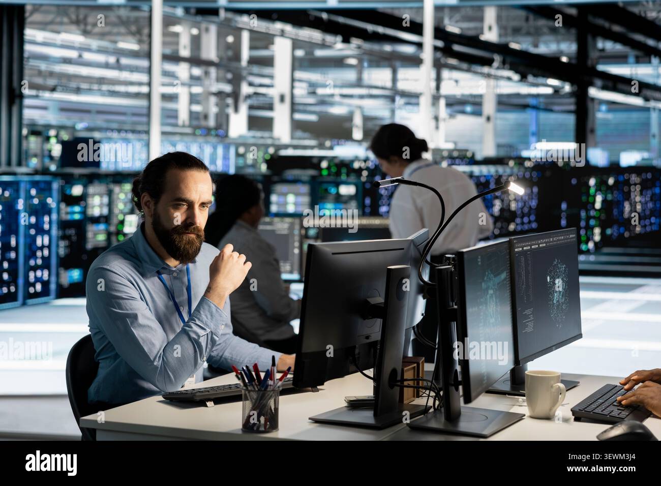 Data center technician uses a computer to run diagnostics, update servers and check infrastructure performance. Stock Photo
