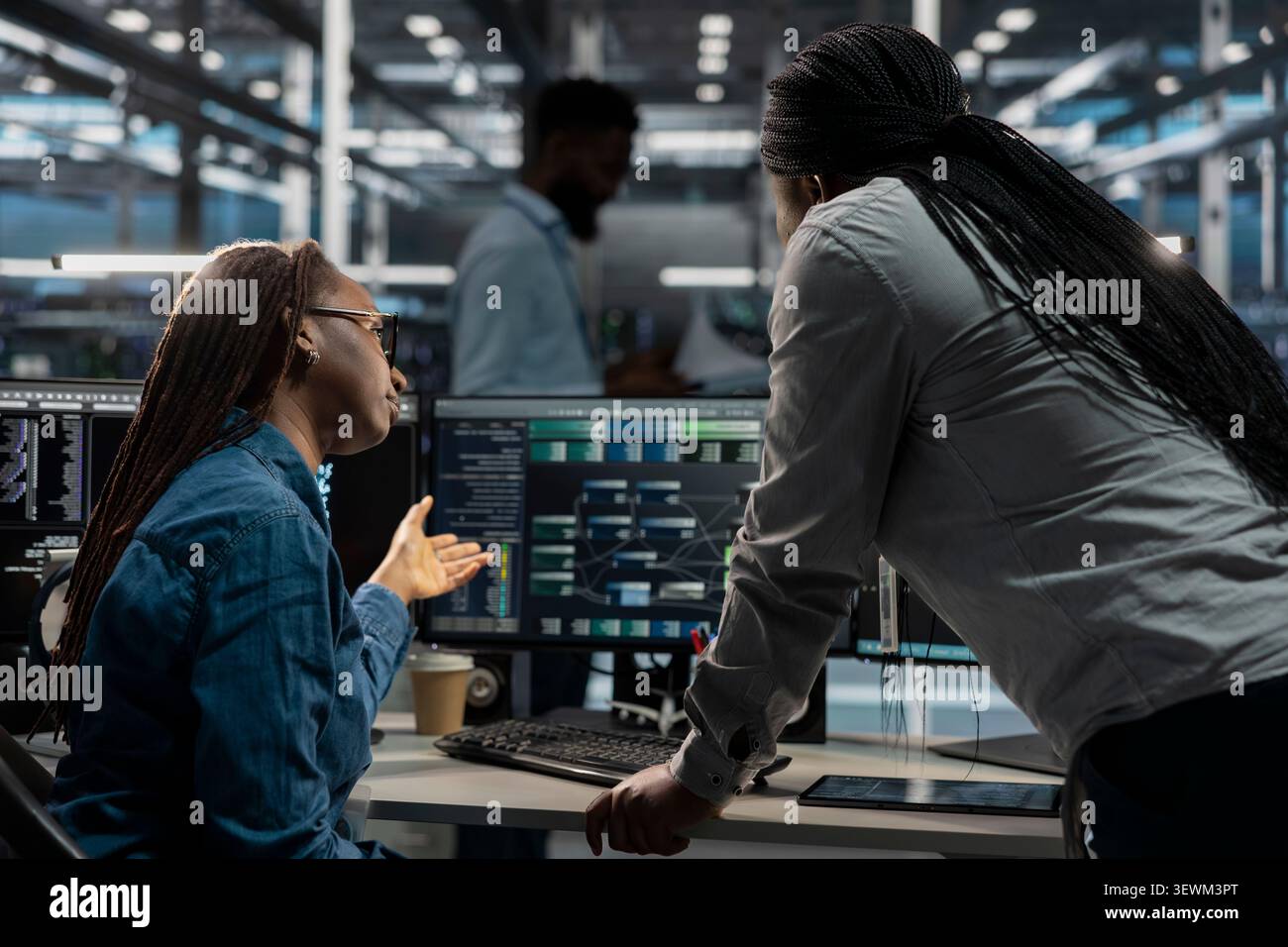 Data center colleagues collaborate on coding and AI automation scripts while reviewing server infrastructure together. Stock Photo