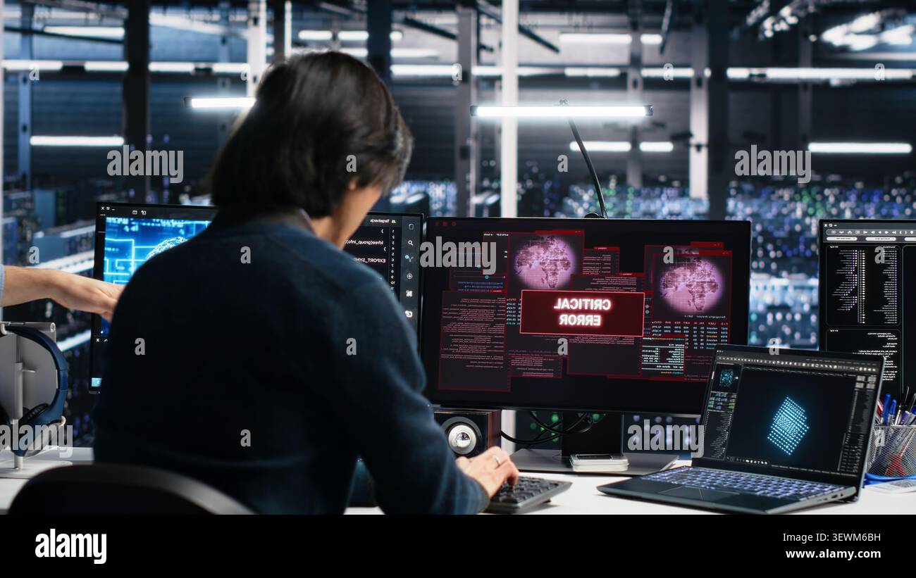 Data center engineering team responds to a warning alert on a digital device while troubleshooting server room systems. Stock Photo