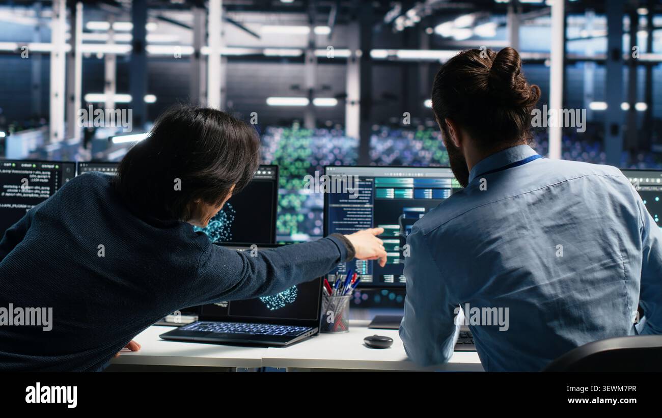 System administrator uses deep learning tools on a digital device in a server room to improve AI operations and system efficiency. Stock Photo