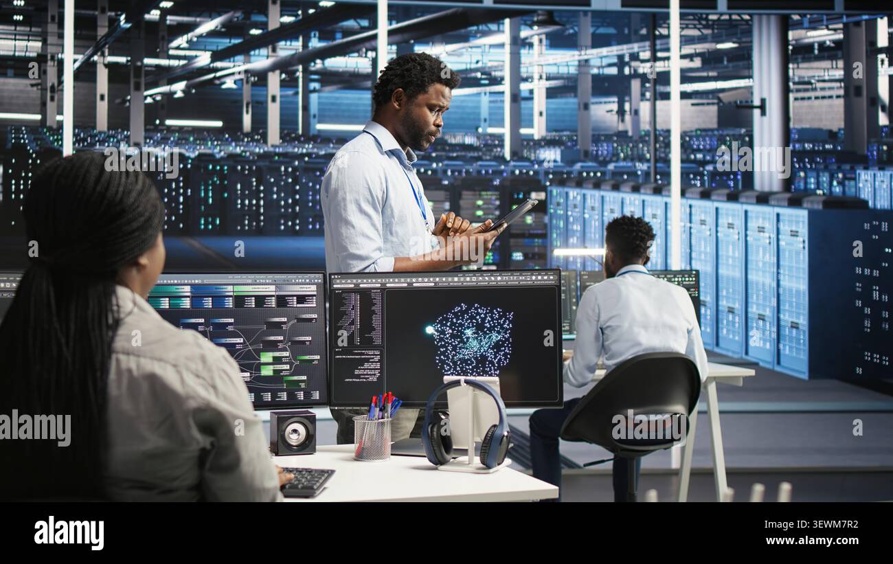 Technician uses a computer workstation in a server farm to categorize unstructured data with node tree systems. Stock Photo