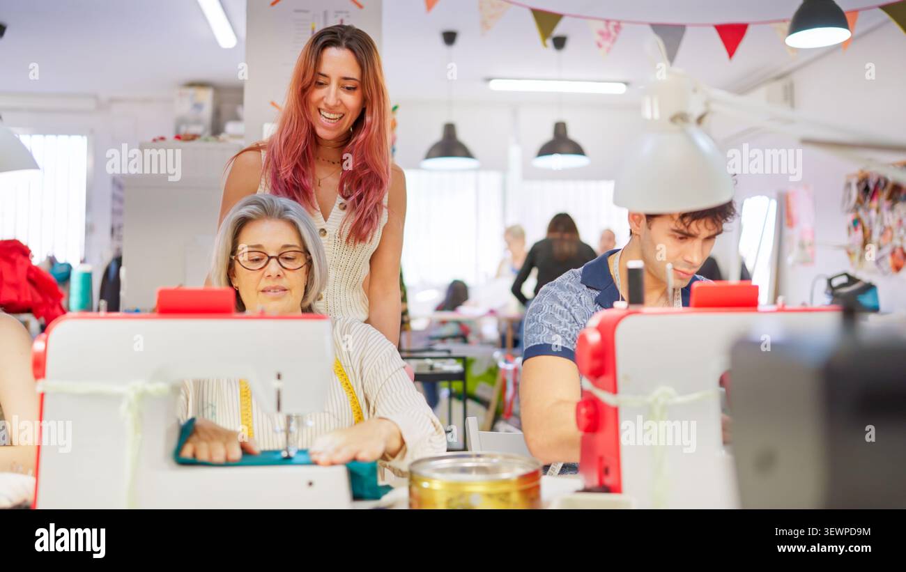 Teacher helping adult student sewing during creative workshop Stock Photo