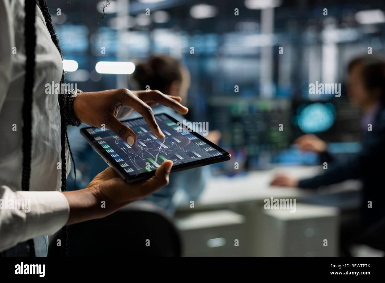 Data center programmer uses a digital tablet in a data center to manage AI systems and optimize server infrastructure. Stock Photo