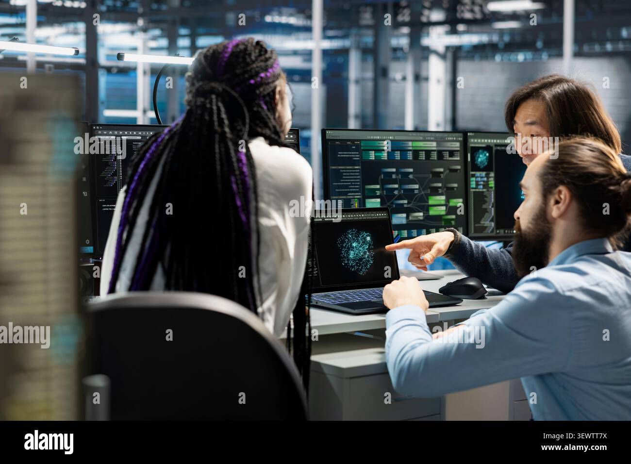 Data center team reviews performance analytics on a computer in a data center to optimize storage systems and resource use. Stock Photo
