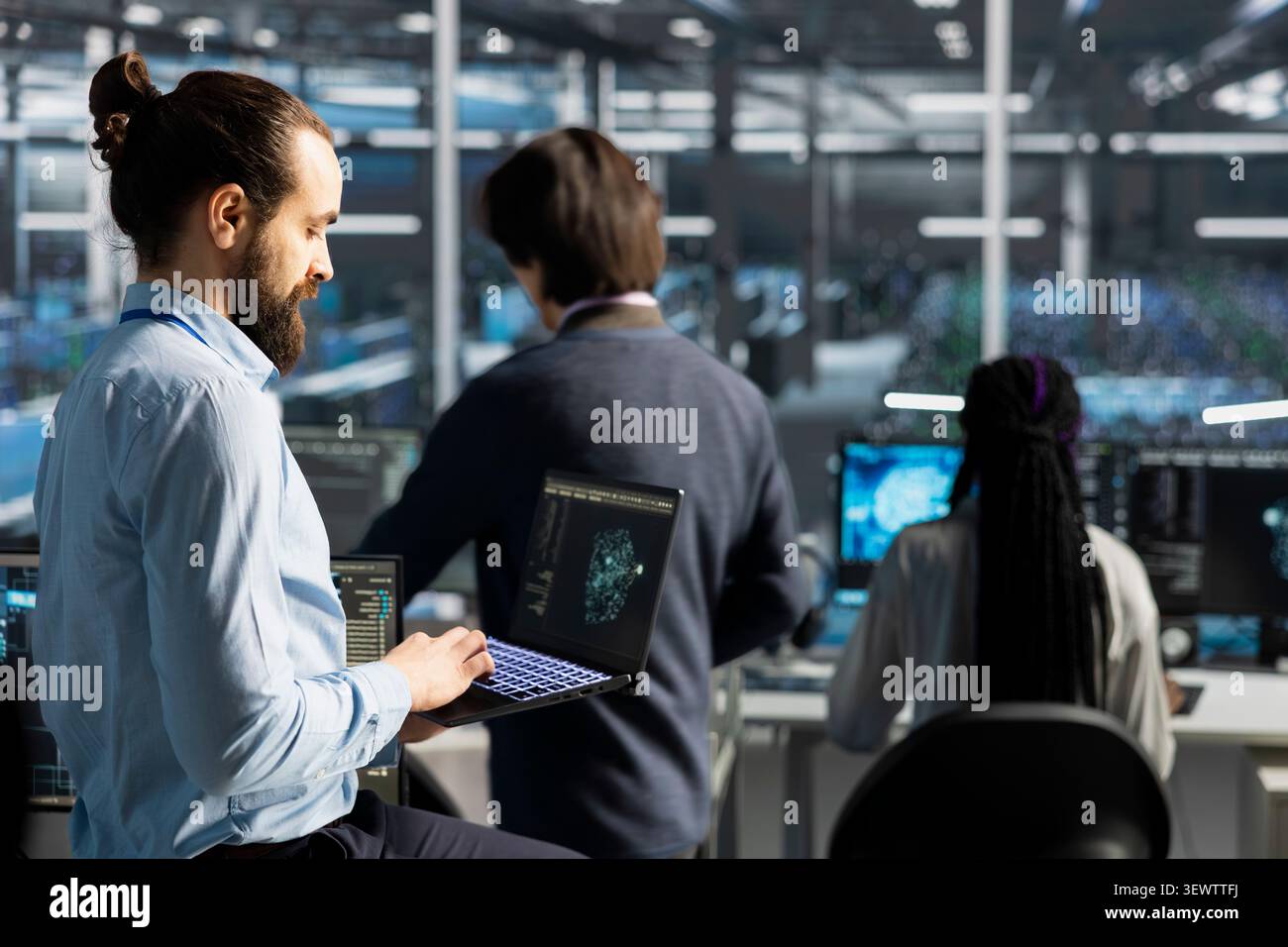 Data center engineer uses a laptop to manage AI training datasets and database workflows inside a server room. Stock Photo