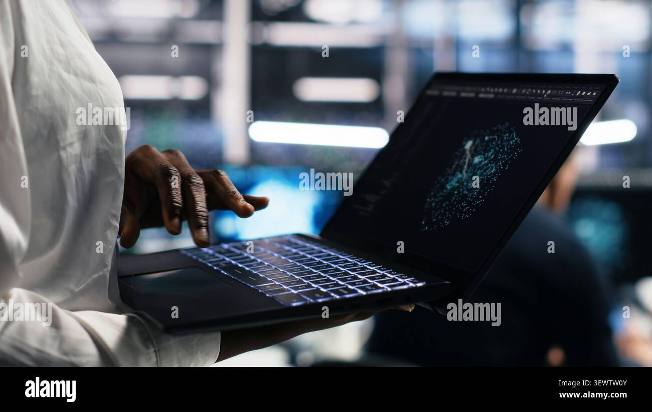 Data center technician reviews AI systems and neural network parameters on a tablet inside a data center. Stock Photo