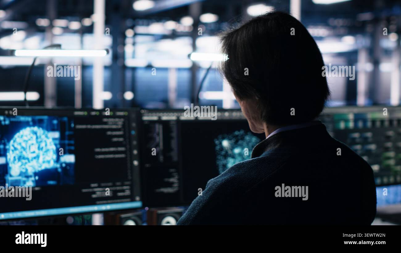 System administrator reviews artificial intelligence systems and machine learning processes inside a data center. Stock Photo
