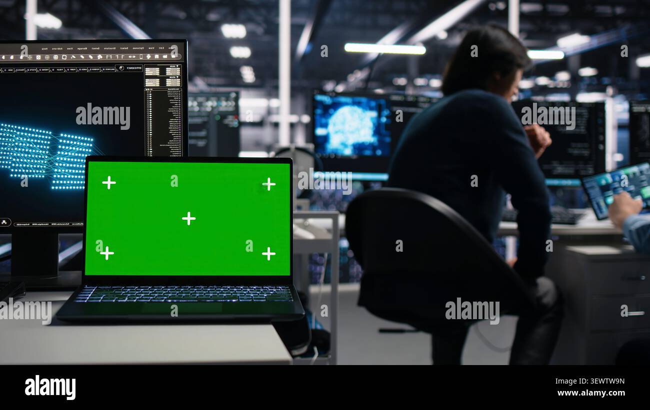 Software developer uses a green screen laptop to manage AI systems, machine learning workflows and server performance. Stock Photo