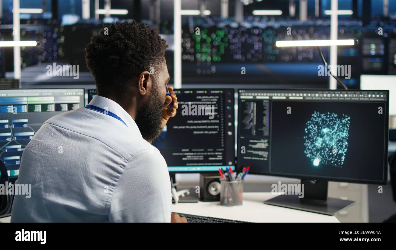 Data infrastructure center computer scientist interprets AI generated data analytics graphs, while african american man in server facility working with AI program showing predictive system metrics. Stock Photo