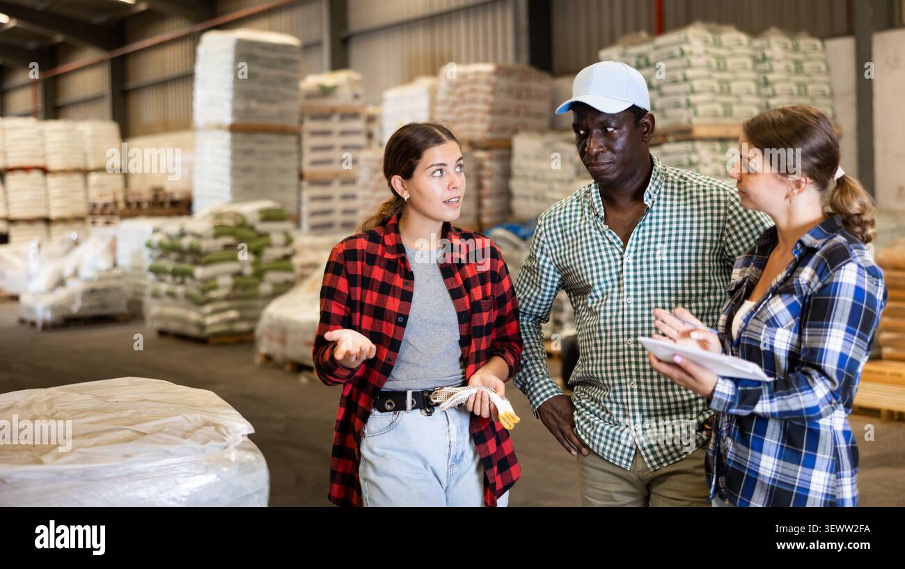 Workers and manager discussing completed work in large warehouse Stock Photo