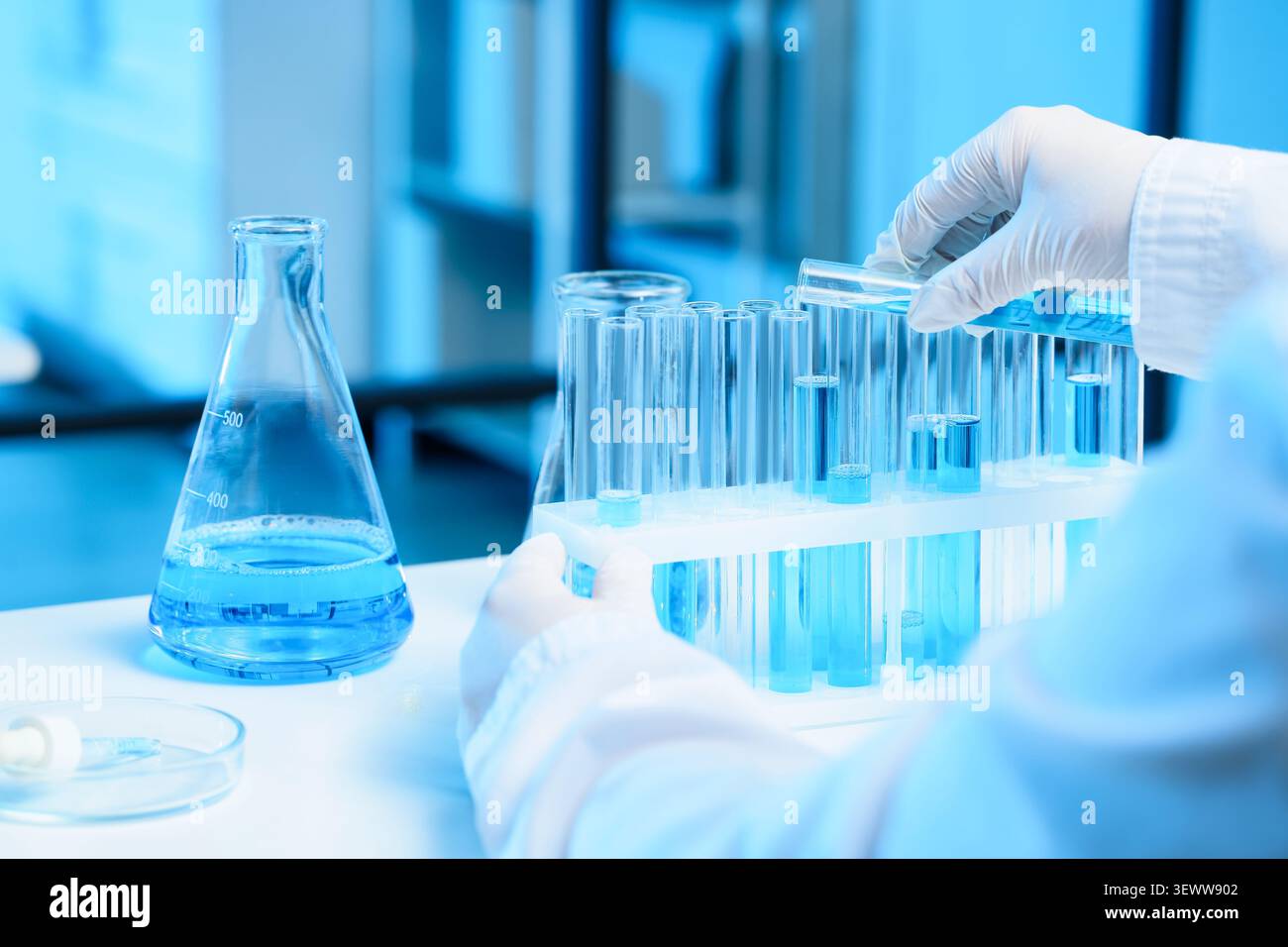 Scientist handling test tubes with blue liquid in laboratory Stock Photo