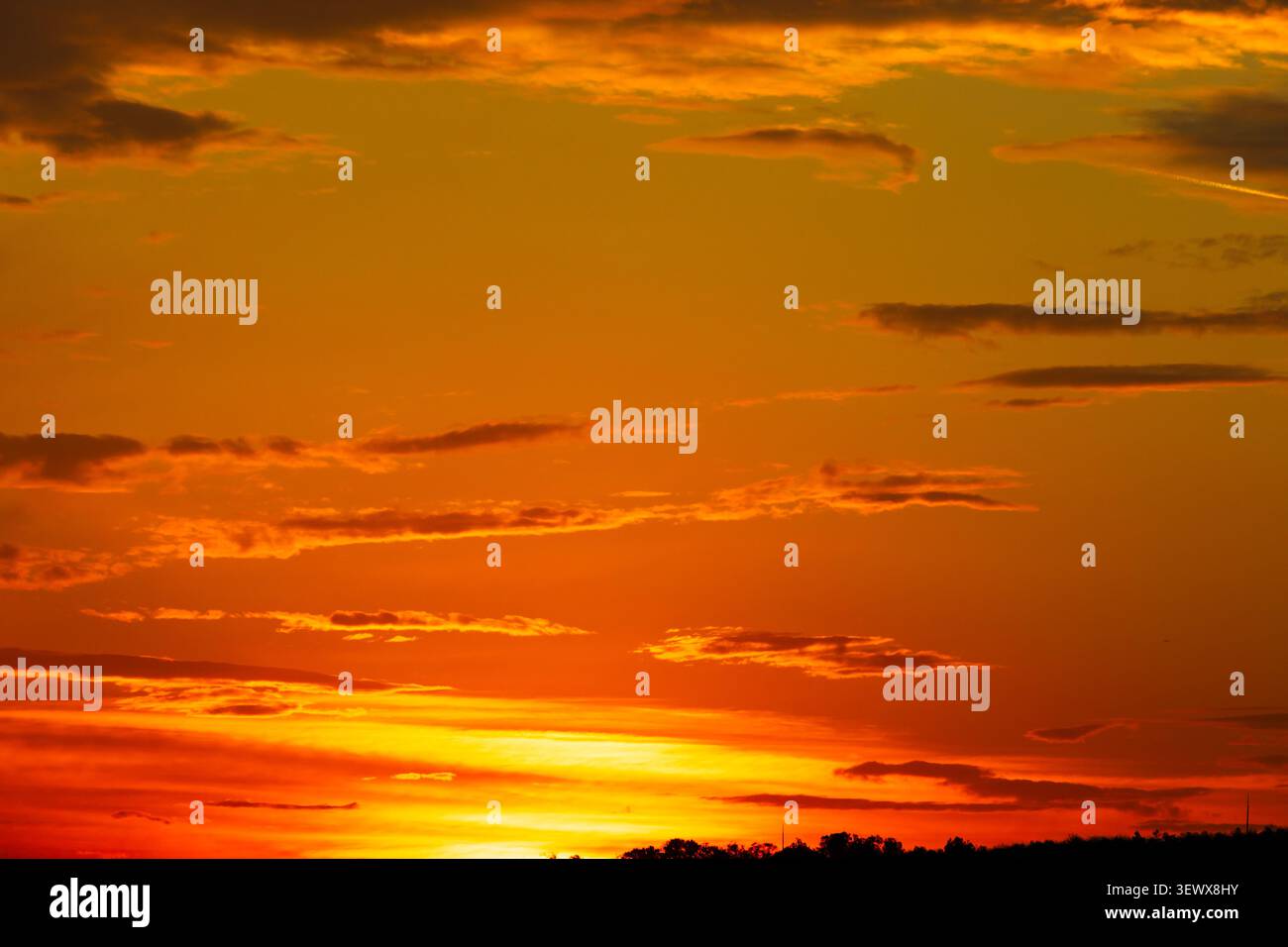 Vibrant orange sky. Dramatic partly cloudy sunset sky background Stock Photo
