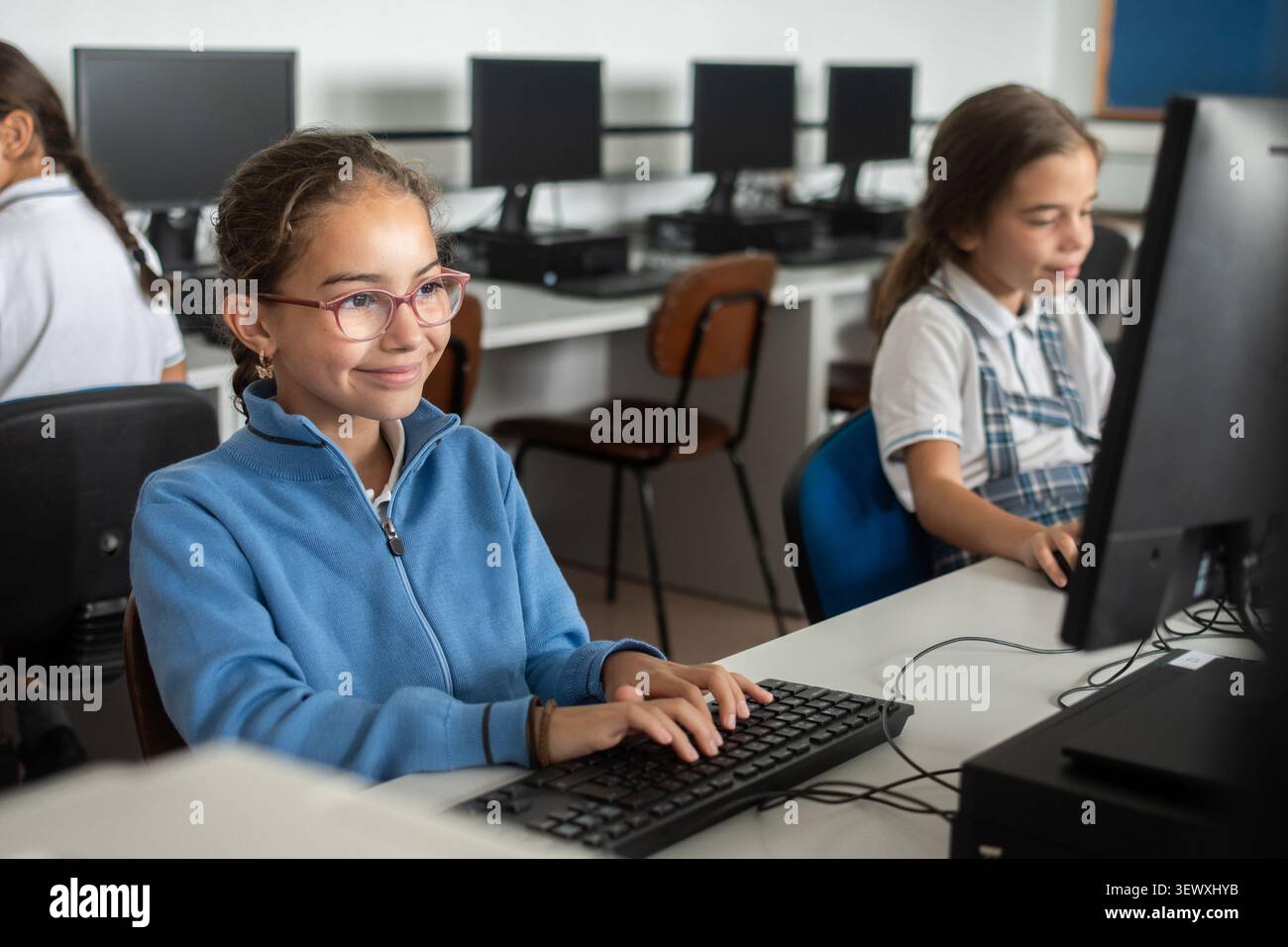 Smiling Elementary School Girl Using Desktop Computer in Computer Lab Stock Photo