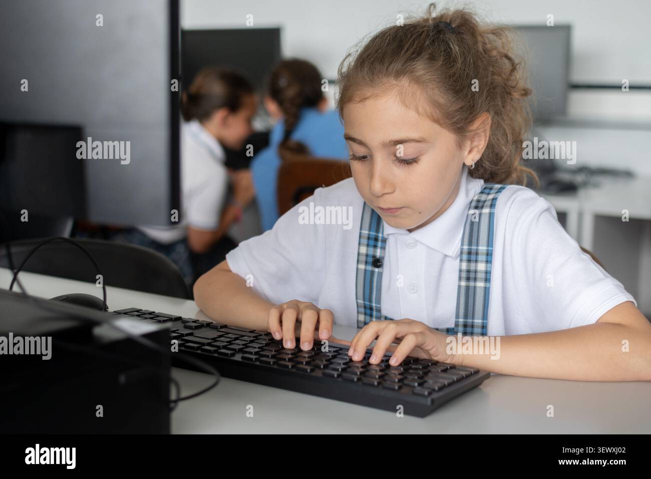 Elementary School Girl Typing on Computer Keyboard in class Stock Photo