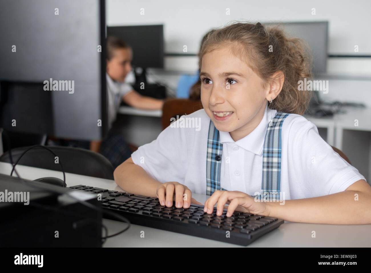 Elementary School Girl Typing on Computer Keyboard in class Stock Photo