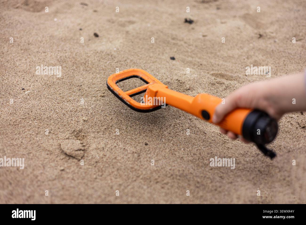 Orange pinpointer metal detector resting on a black backpack Stock Photo